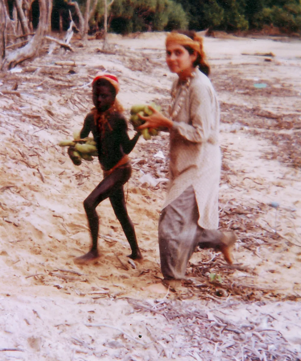 Madhumala, wearing seashell ornaments gifted by the women of the community, helps a Jarawa girl carry bananas and coconuts from the seashore to her hut